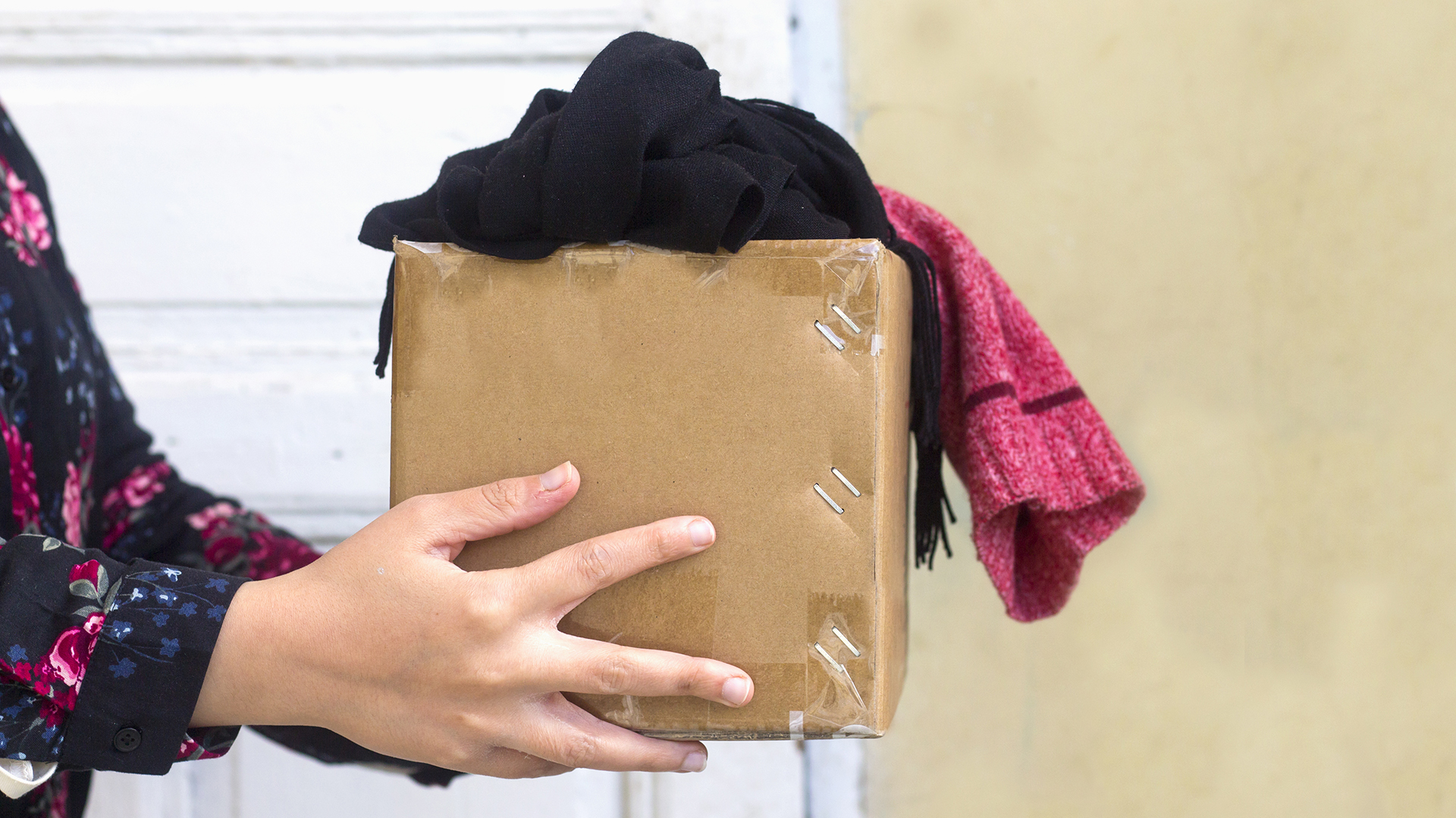 woman holding cardboard box with clothing during clothing drive